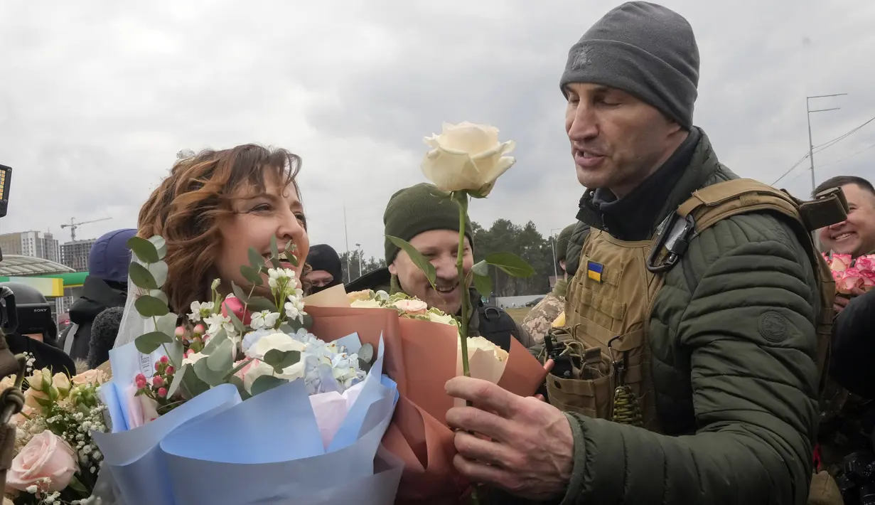 Mantan juara dunia tinju kelas berat Ukraina Wladimir Klitschko (kanan) mengucapkan selamat kepada anggota Pasukan Pertahanan Teritorial Ukraina Lesia Ivashchenko dan Valerii Fylymonov yang baru menikah dalam upacara pernikahan di pos pemeriksaan di Kiev, 6 Maret 2022. (AP/Efrem Lukatsky)