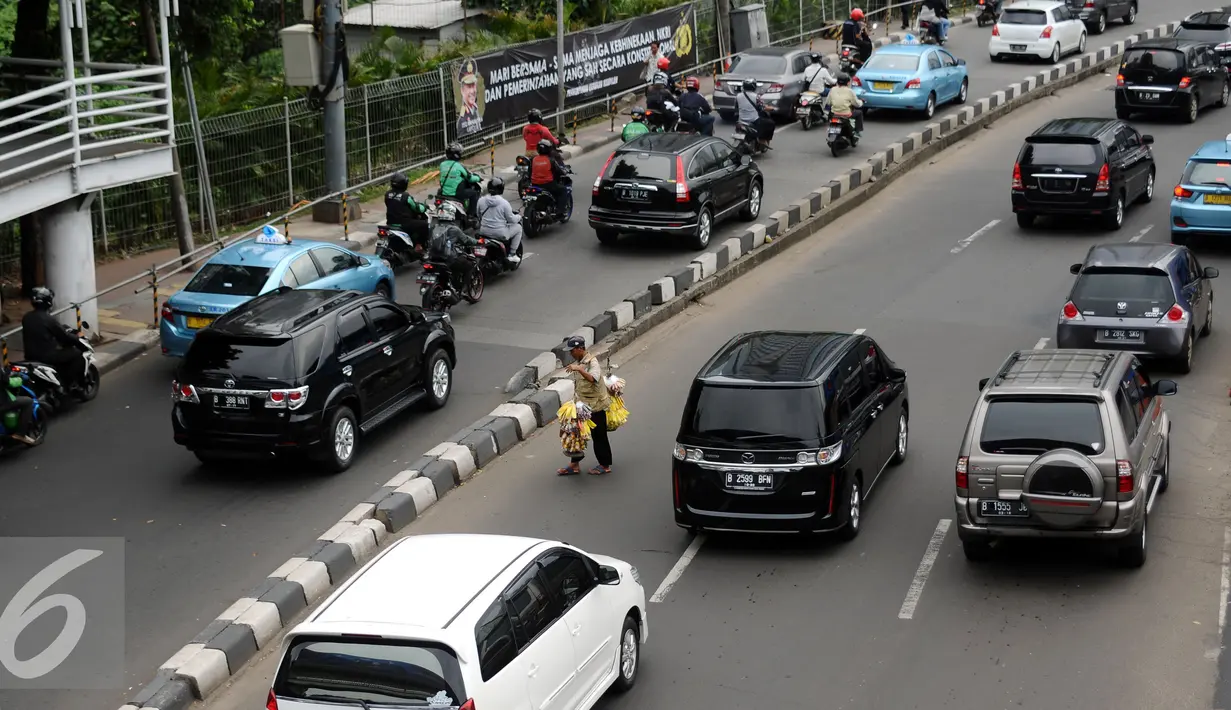 Pedagang asongan menyebrang Jalan Jenderal Sudirman Jakarta, Jumat (25/11). Dibayangi aksi massa besar-besaran Jumat (25/11) arus lalu lintas sejumlah ruas jalan protokol di Jakarta terlihat normal. (Liputan6.com/Helmi Fithriansyah)