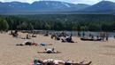 Orang-orang berjemur di pantai di Loch Morlich dekat Aviemore, di Skotlandia, (28/5). Cuaca panas tengah melanda sebagian besar wilayah di Inggris. (AP Photo/Jane Barlow)