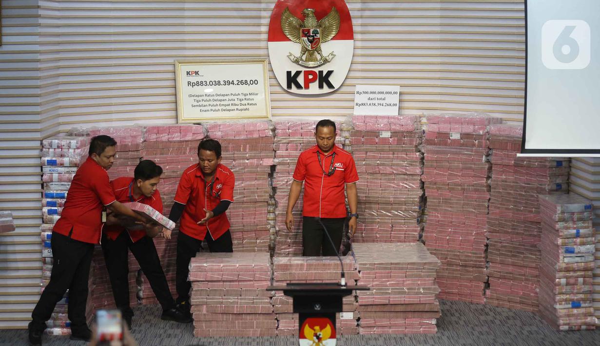 Petugas merapikan tumpukan uang sebesar Rp 300 miliar yang dipamerkan di gedung Merah Putih Komisi Pemberantasan Korupsi (KPK), Jakarta, Kamis (20/11/2025). (Liputan6.com/Helmi Fithriansyah)