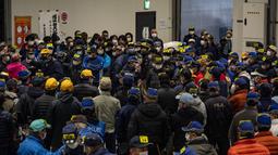 Para tengkulak yang mengenakan masker untuk mencegah penularan COVID-19 berpartisipasi dalam lelang tuna di Pasar Toyosu, Tokyo, Jepang, 5 Januari 2021. Untuk lelang tahun ini, para tengkulak diwajibkan menggunakan masker dan membersihkan tangan saat memeriksa tekstur tuna. (Philip FONG/AFP)