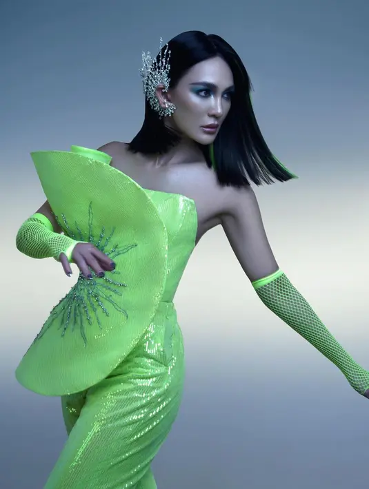 Luna Maya tampil futuristik dalam balutan kostum hijau. Kostum hijau kekuningan ini memiliki siluet jumpsuit dengan aksen bentuk kipas di bagian depan dada. Penampilannya sempurna dengan heels dan gloves panjang berwarna senada. Foto: Instagram.