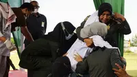 Sejumlah anggota polisi Syariah membantu seorang wanita setelah dia dicambuk di depan umum di Lhokseumawe, Aceh, Senin (28/6/2021). Wanita yang didakwa telah melakukan hubungan seks pranikah itu dihukum dengan 100 cambukan. (Azwar Ipank/AFP)