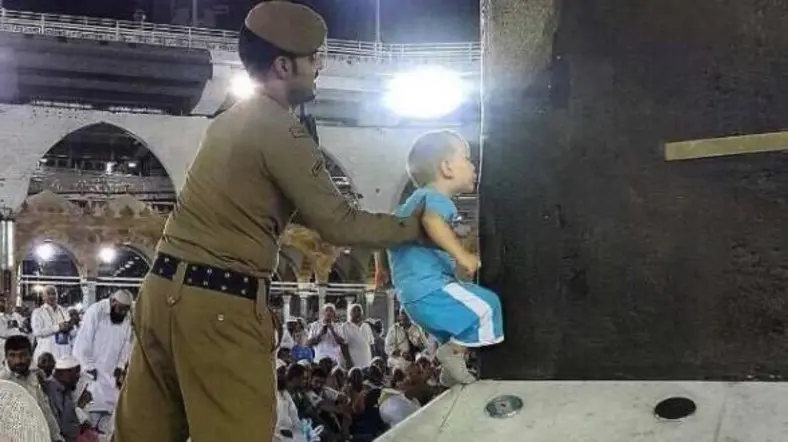 Foto petugas membantu bocah mencium Kakbah yang menuai pujian netizen. (Twitter)