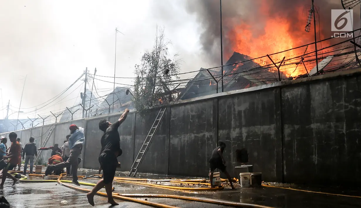 Warga mencoba memadamkan api yang membakar pemukiman padat penduduk di kawasan Manggarai, Jakarta, Rabu (10/7/2019). Sebanyak 27 Unit mobil pemadam kebakaran diterjunkan untuk memadamkan api yang melanda pemukiman di dekat Stasiun Manggarai tersebut. (Kapanlagi.com/Budy Santoso)
