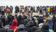 Pengungsi Rohingya duduk bersama di tanah setelah mereka tiba dengan perahu di Pantai Kalee, Laweung, Kabupaten Pidie, Provinsi Aceh, Indonesia, Selasa (14/11/2023). Hampir 200 pengungsi Rohingya, termasuk banyak perempuan dan anak-anak, terdampar di provinsi paling barat Indonesia pada 14 November, menurut laporan setempat. (Jon S./AFP)