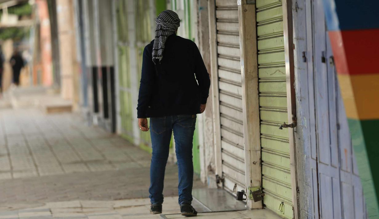 Seorang pria melewati toko-toko yang tutup di kota Gaza, (7/12). Usai Presiden AS, Donald Trump mengumumkan Yerusalem sebagai ibu kota Israel suasana sepi terlihat di kawasan tersebut. (AFP Photo/ Mohammed Abed)