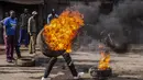 Seorang pengunjuk rasa membawa ban yang terbakar untuk memblokir jalan di lingkungan Kibera di Nairobi, Kenya Rabu, 12 Juli 2023. Pengunjuk rasa anti-pemerintah berdemonstrasi di sejumlah kota Kenya menentang pajak yang baru diberlakukan dan biaya hidup. (AP Photo/Samson Otieno)