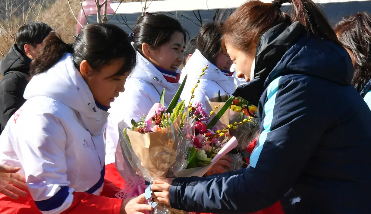 Tim Korea Selatan (kanan) memberi bunga kepada tim hoki es Korea Utara saat tiba di pusat pelatihan nasional Jincheon, Korsel (25/1). (AFP Photo/Pool/ Kyung-Seok)