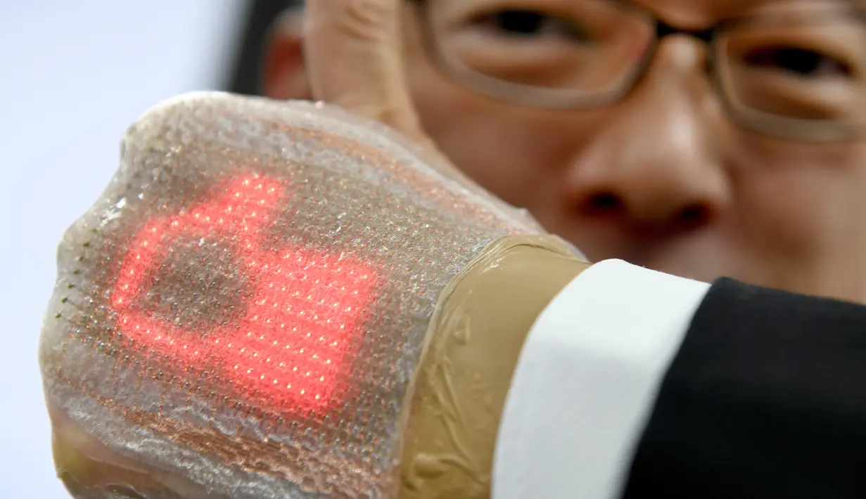 Seorang pria menunjukkan layar elastis ultra tipis yang dilengkapi dengan dioda di Tokyo, Jepang (14/2). Alat ini dapat menerima pesan, termasuk emoji dan dapat memantau kesehatan penggunanya. (AFP Photo/Toru Yamanaka)