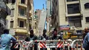 Aparat kepolisian menutup jalan dekat sebuah apartemen berlantai 13 yang mengalami kemiringan hingga mencapai blok apartemen lainnya di Alexandria, Mesir, Sabtu (3/6). Peristiwa itu memaksa polisi untuk mengevakuasi seluruh penghuni bangunan. (AP Photo)