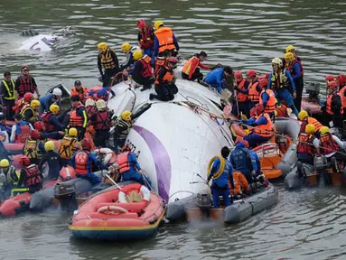 Petugas berusaha mengevakuasi penumpang pesawat milik TransAsia Airways di sungai Taipei, Taiwan, Rabu (4/2/2015). Pesawat yang mengangkut 58 penumpang dan awak pesawat itu terhempas ke sungai saat hendak lepas landas. (AFP PHOTO/Sam Yeh)