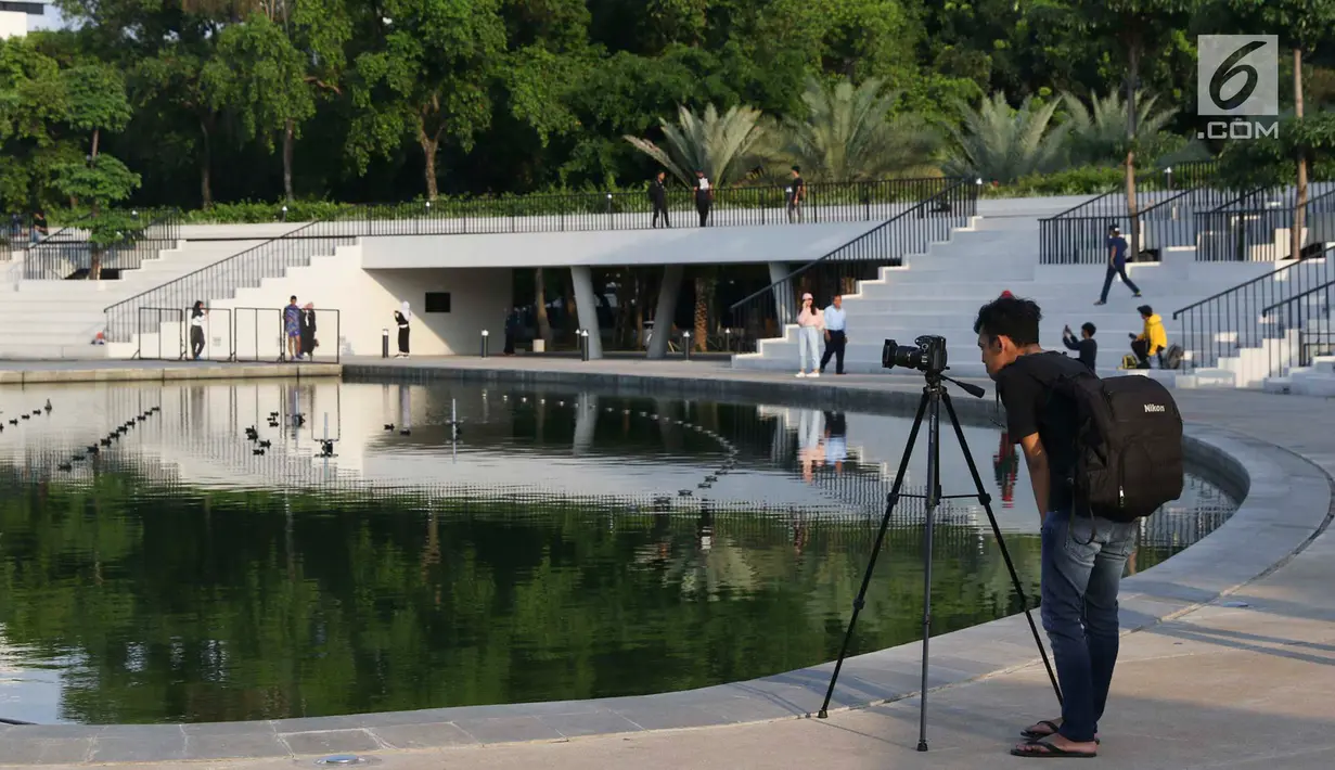 Seorang pria mengambil foto di Taman Lapangan Banteng, Jakarta, Rabu (13/2). Selain sebagai tempat berolahraga, taman yang diresmikan pascarevitaslisasi Juli 2018 lalu, kini menjadi lokasi favorit warga berburu foto. (Liputan6.com/Immanuel Antonius)