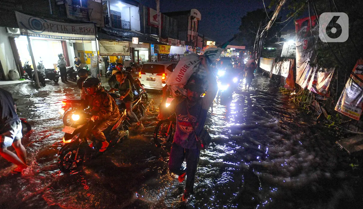 Pengendara bermotor melewati genangan air di kawasan Jalan Dr. Setiabudi, Pamulang, Tangerang Selatan, Rabu (6/12/2023). (merdeka.com/Arie Basuki)