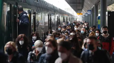 Para penumpang yang mengenakan masker berjalan di peron setelah turun dari kereta regional di stasiun Cadorna di Milan, Senin (26/4/2021). Italia kembali dibuka secara bertahap pada hari Senin setelah enam bulan memberlakukan lockdown untuk menghambat penyebaran Covid-19. (AP Photo/Antonio Calanni)