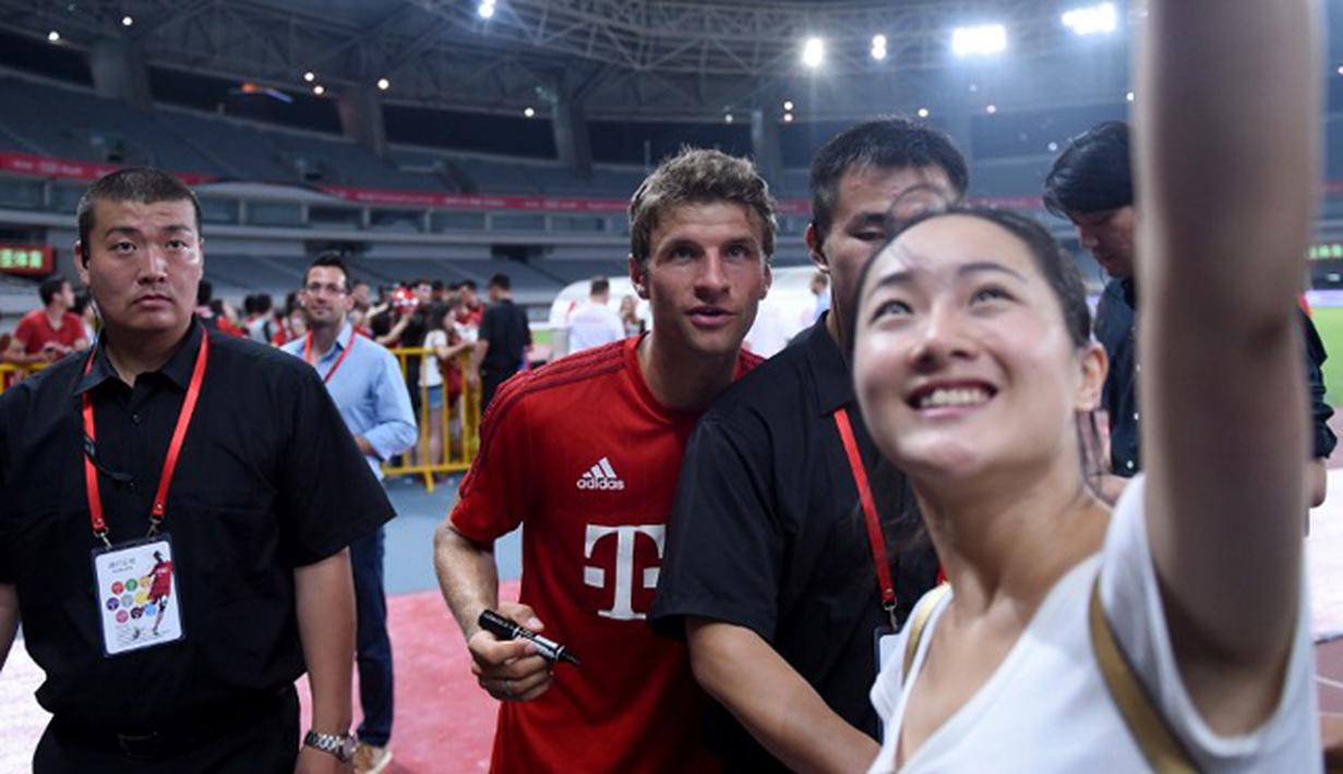 Penyerang Bayern Muenchen, Thomas Mueller berselfie bersama seorang fans usai sesi latihan di Shanghai, China, (19/7/2015). Bayern mengunjungi Cina untuk menggelar Tur Pra-musim. (AFP PHOTO/JOHANNES EISELE)