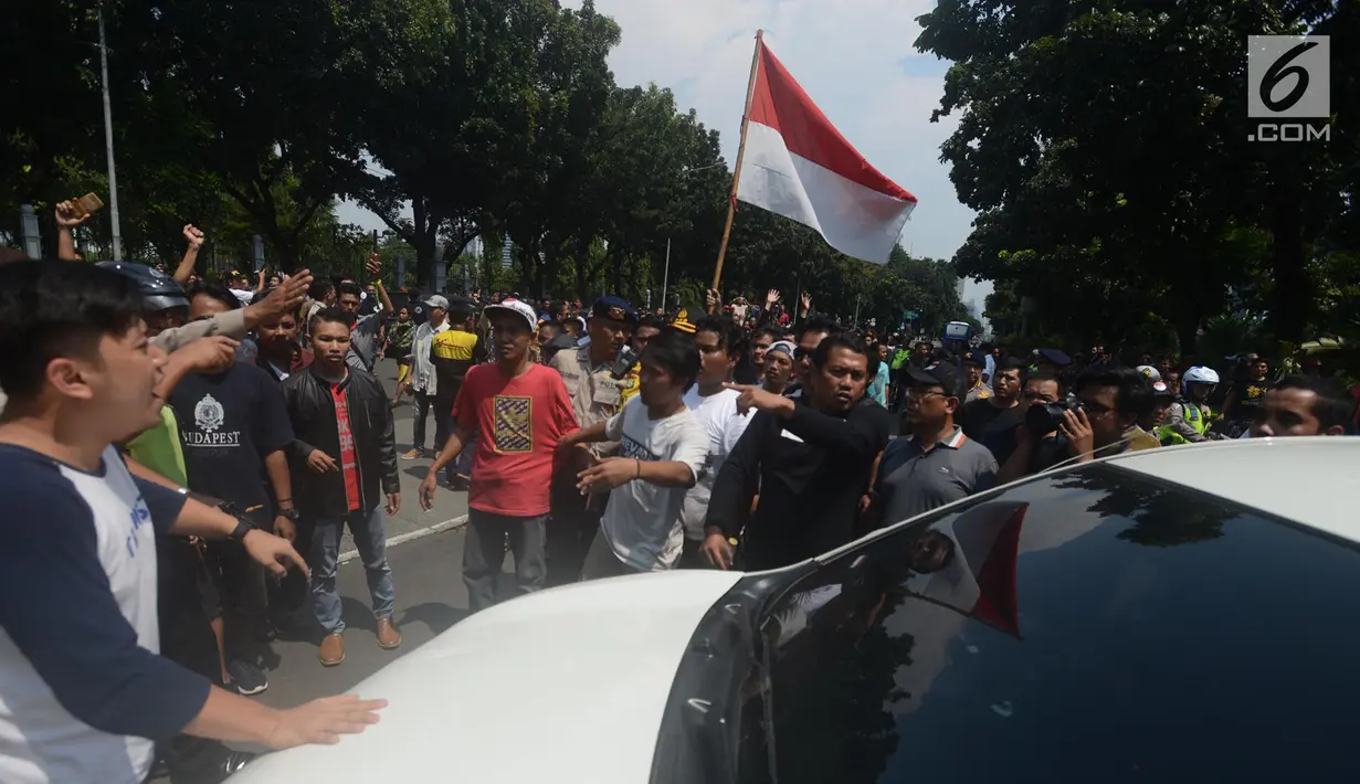 Massa driver taksi online yang tergabung dalam Aliando menggelar demo di Jalan Medan Merdeka Barat, Jakarta, Rabu (28/3). Dalam aksinya para driver online ini sempat bersitegang dengan polisi. (Merdeka.com/Imam Buhori)
