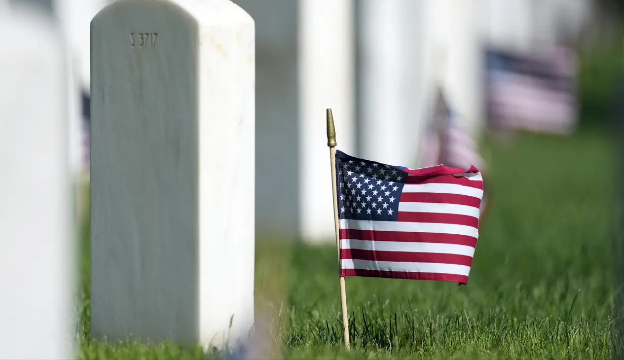 Bendera Amerika Serikat berdiri dekat batu nisan di Pemakaman Nasional Fort Logan, Sheridan, Colorado, Amerika Serikat, 30 Mei 2022. (AP Photo/David Zalubowski)