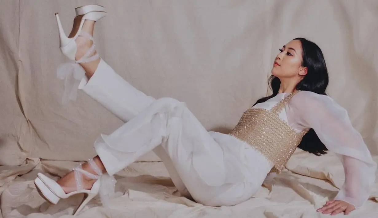 Photoshoot memukau Sherina Munaf pakai outfit berwarna putih. Ia memadukan jumpsuit putih dengan top jewelry keemasan yang mewah. [Foto: Instagram/sherinamunaf]