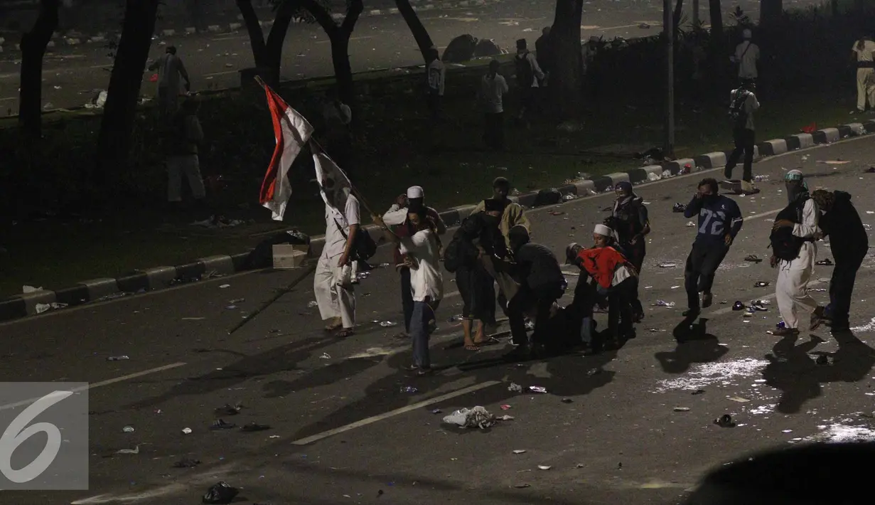 Pendemo berusaha menyelamatkan kawannya yang terkapar saat bentrok terjadi di jalan Medan Merdeka Barat, Jakarta, Jumat (4/11). (Liputan6.com/Faizal Fanani)