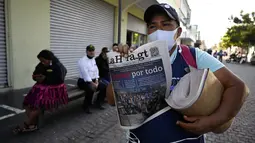 Seorang perempuan menjual edisi cetak terakhir surat kabar La Hora di jalan-jalan Pusat Sejarah Guatemala City pada 12 November 2021. Setelah 101 tahun, surat kabar malam La Hora de Guatemala mencetak edisi terakhirnya pada hari Jumat dan nantinya hanya edisi online yang tersedia (Johan ORDONEZ/AFP)