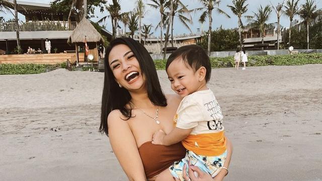 Vanessa Angel menggendong putranya, Gala Sky dalam momen liburan di sebuah pantai.