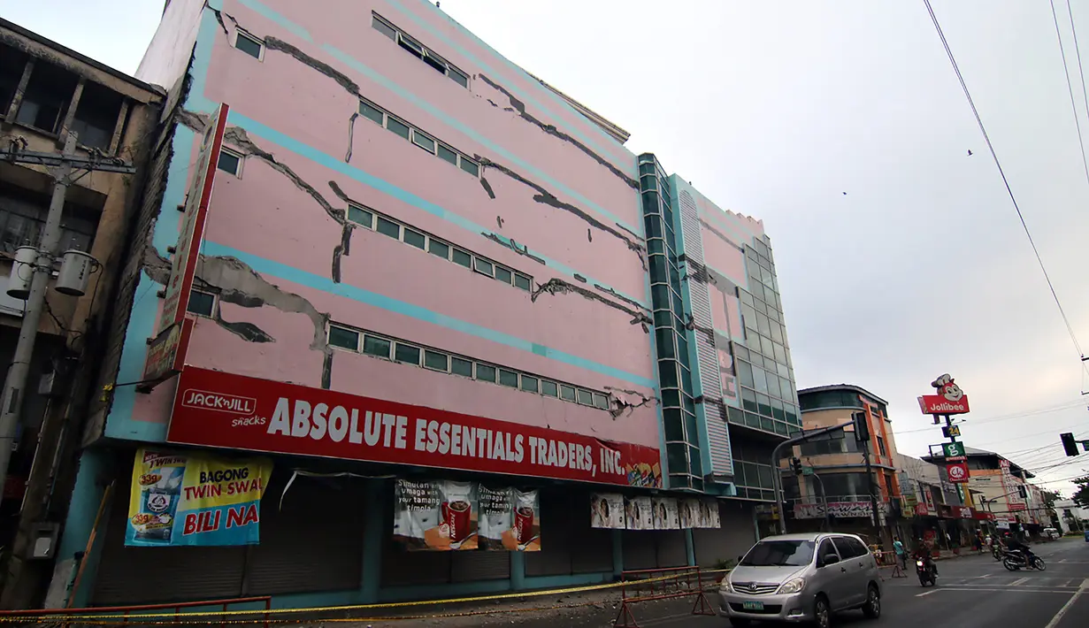Sejumlah pengedara melitas di depan gedung yang rusak akibat gempa 6,5 SR yang melanda Surigao City, Pulau Mindanao, Filipina (11/2). Gempa tersebut mengakibatkan sedikitnya empat orang tewas dan 120 orang lainnya terluka. (AFP/Erwin Mascarinas)
