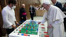 Paus Fransiskus bermain foosball atau sepak bola meja melawan Natale Tonini, presiden asosiasi Sport Toscana Calcio Balilla, pada akhir audiensi umum mingguan di Vatikan, Rabu (18/8/2021). Paus Fransiskus memang dikenal hobi bermain dan menonton sepak bola. (Vatican Media via AP)