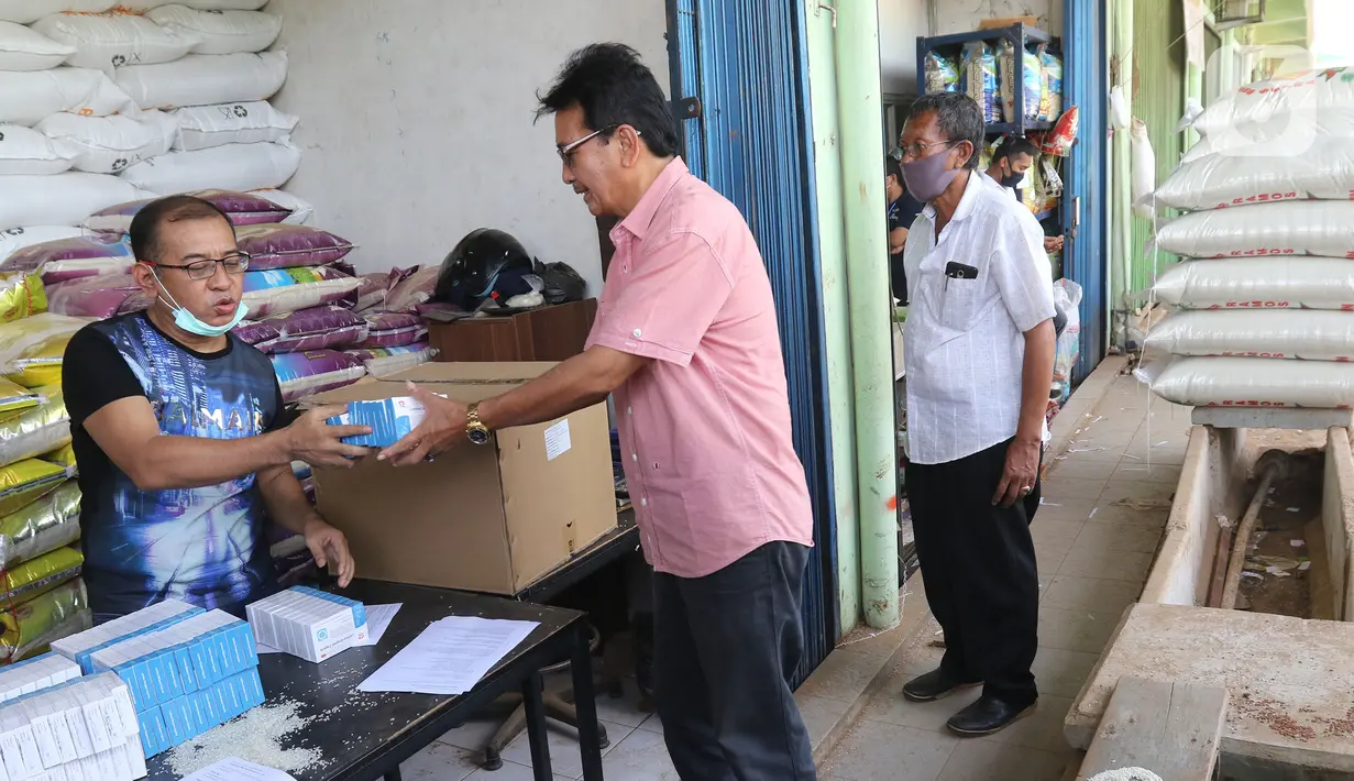 Wakil Ketua Umum Persatuan Pengusaha Penggilingan Padi dan Beras (Perpadi) Billy Haryanto memberikan obat ke buruh di Pasar induk beras Cipinang, Jakarta, Sabtu (16/5/2020). (Liputan6.com/Herman Zakharia)