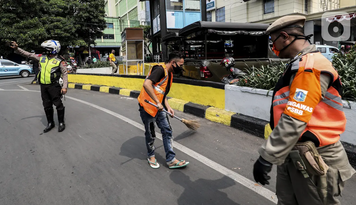 Warga pelanggar Pembatasan Sosial Berskala Besar (PSBB) dihukum menyapu jalanan saat terjaring razia masker di wilayah Tanah Abang, Jakarta, Senin (14/9/2020). Razia tersebut guna menekan kasus penyebaran COVID-19 di Jakarta pada masa PSBB. (Liputan6.com/Johan Tallo)