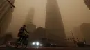 Pesepeda melewati gedung-gedung perkantoran di tengah badai pasir pada jam sibuk pagi hari di kawasan pusat bisnis di Beijing, Senin (15/3/2021). (AP Photo/Andy Wong)