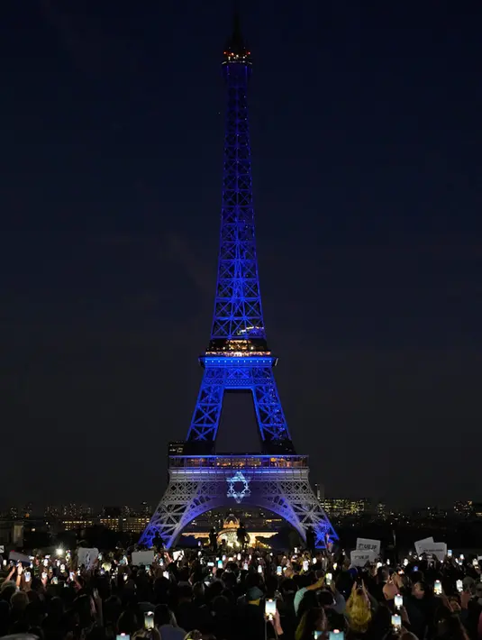 <p>Warga menyaksikan Menara Eiffel yang diterangi dengan warna-warna Israel setelah demonstrasi untuk menunjukkan dukungan kepada Israel di Paris, Prancis, Senin (9/10/2023). Hal ini dilakukan dua hari setelah pejuang Hamas melancarkan serangan multifront yang belum pernah terjadi sebelumnya terhadap Israel yang menewaskan lebih dari 700 orang. (AP Photo/Michel Euler)</p>