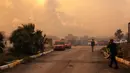 Warga dan petugas pemadam kebakaran berusaha memadamkan api saat asap dan kobaran api membumbung tinggi dari sebuah kawasan hutan menyusul kebakaran hutan di distrik Seferihisar, Izmir, Turki, pada 30 Juni 2025. (Ahmet Ayberk Cimen/AFP)