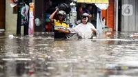 Warga melintasi genangan banjir yang melanda kawasan Kemang Utara, Jakarta, Kamis (4/1/2024). (Liputan6.com/Herman Zakharia)