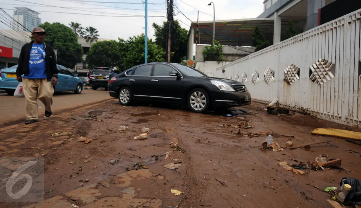 Warga melintas di sisi lumpur sisa banjir di Jalan Kemang Raya, Minggu (28/8). Sejumlah kendaraan terendam air di kawasan Kemang Raya pasca hujan deras di Jakarta pada Sabtu (27/8). (Liputan6.com/Helmi Fithriansyah)
