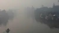 Perahu melintas di Sungai Andai yang tertutup kabut asap di Banjarmasin, Kalsel, Senin (3/10).(Antara) 