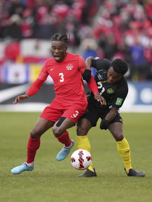 Bek timnas Kanada Sam Adekugbe berebut bola dengan bek Jamaika Javain Brown pada laga Kualifikasi Piala Dunia 2022 Zona CONCACAF di Venue BMO Field, Senin (28/3/2022) dini hari WIB. Kanada lolos ke Piala Dunia 2022 usai melibas Jamaika dengan skor 4-0. (Nathan Denette/The Canadian Press via AP)