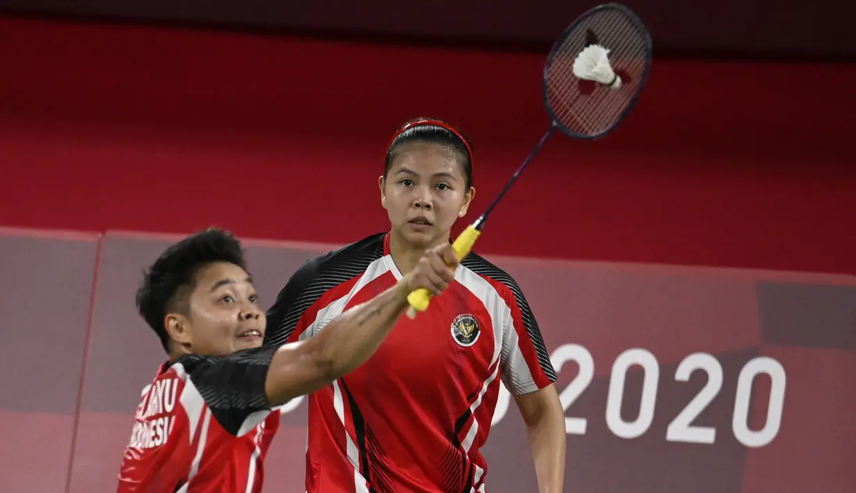 Ganda putri Indonesia Greysia Polii (tengah) menyaksikan Apriyani Rahayu melakukan pukulan pada pertandingan pertama Grup A cabang bulu tangkis melawan wakil Malaysia di Musashino Forest Sport Plaza, Sabtu (24/7/2021). Greysia Polii / Apriyani menang 21-17. (Alexander NEMENOV/AFP)
