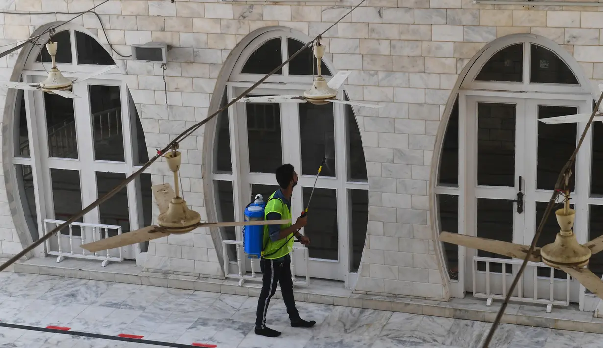 Seorang pekerja menyemprotkan disinfektan di masjid menjelang Ramadan selama penguncian nasional yang diberlakukan pemerintah sebagai tindakan pencegahan terhadap coronavirus COVID-19, di Karachi, Pakistan (21/4/2020). (AFP/Asif Hassan)