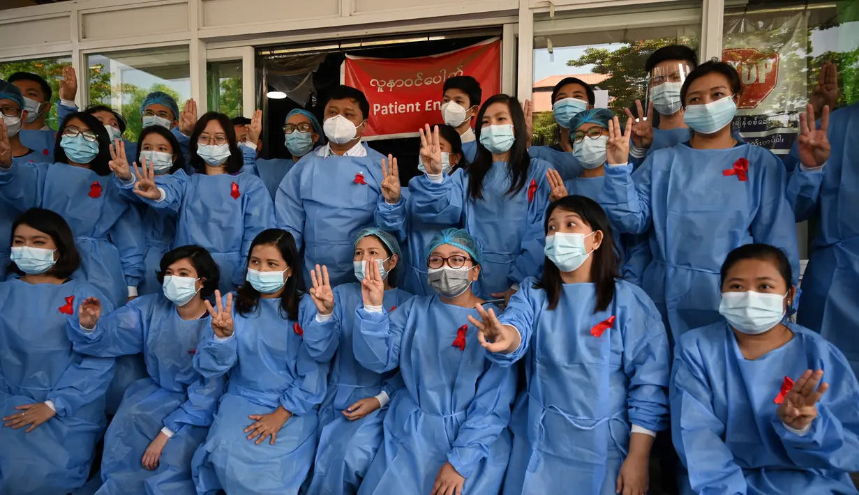 Tenaga medis mengenakan pita merah di seragamnya memberi hormat tiga jari di Rumah Sakit Umum Yangon di Yangon pada 3 Februari 2021 ketika seruan untuk pembangkangan sipil semakin meningkat menyusul kudeta militer yang menahan pemimpin sipil Aung San Suu Kyi. (STR / AFP)