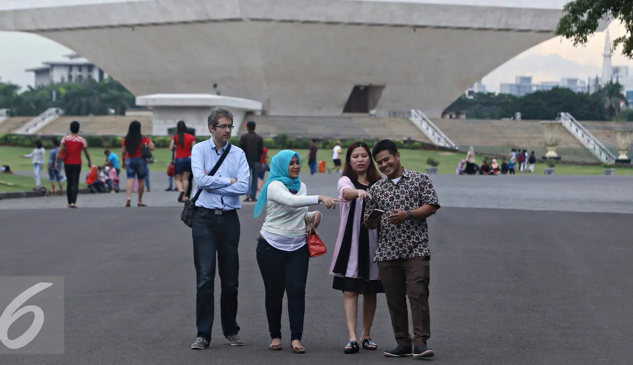 Pengunjung berjalan sambil berbincang di kawasan Monas, Jakarta, Kamis (31/3/2016). Rutinnya penertiban membuat kawasan Monas kini lebih tertata rapih dan bebas dari PKL. (Liputan6.com/Imamnuel Antonius)