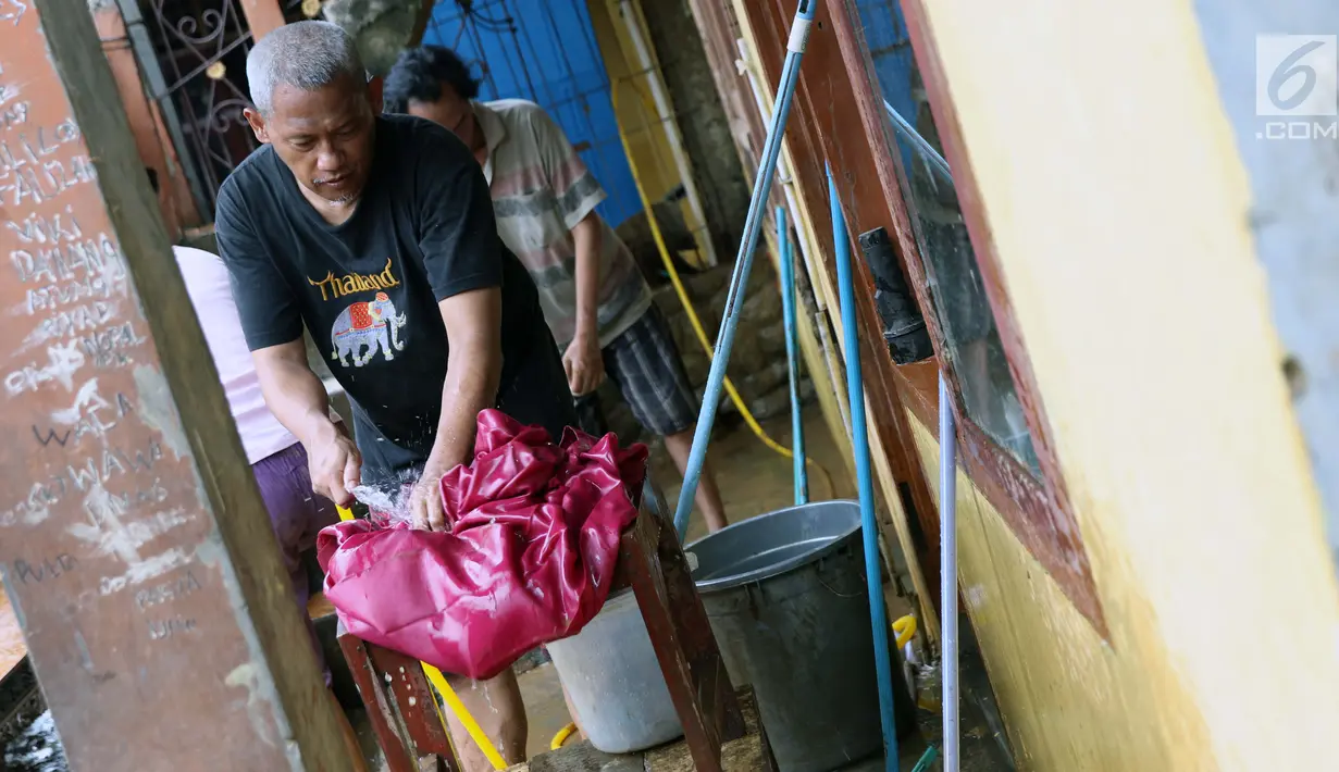 Warga membersihkan lumpur sisa banjir yang melanda kawasan Rawajati, Jakarta, Sabtu (27/4). Banjir akibat luapan air sungai Ciliwung sempat melanda kawasan ini pada Jumat (26/4). (Liputan6.com/Helmi Fithriansyah)