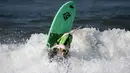 Seekor anjing ambil bagian selama acara tahunan Surf City Surf Dog di Huntington Beach, California padaSabtu (25/9/2021). Para anjing menaklukkan ombak di atas papan surfingnya. (AP Photo/Ringo H.W. Chiu)