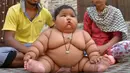 Bayi perempuan, Chahat Kumar, didampingi orangtuanya, Suraj dan Reenu, di rumah mereka di Amritsar, India, Senin (17/4). Meski usianya masih 8 bulan, berat badannya yang mencapai 17 kg membuat Chahat dijuluki bayi terberat di dunia. (NARINDER NANU/AFP)