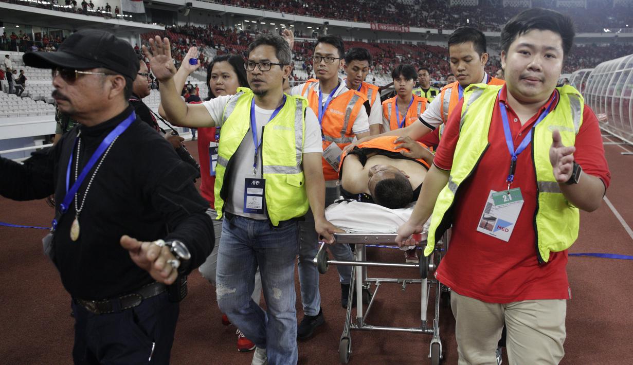Seorang suporter Malaysia dievakuasi petugas karena terjatuh ketika dievakuasi karena serangan suporter Timnas Indonesia saat laga Kualifikasi Piala Dunia 2022 di SUGBK, Jakarta, Kamis (5/9). (Bola.com/Vitalis Yogi Trisna)