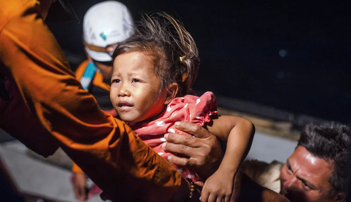 Tim penyelamat membantu anak untuk menaiki kapal saat dievakuasi dari Pulau Sebuku di perairan Selat Sunda (28/12). Ratusan orang tewas dalam Tsunami Selat Sunda yang melanda Sumatera dan Jawa tanpa peringatan akhir pekan lalu. (AP Photo/Fauzy Chaniago)