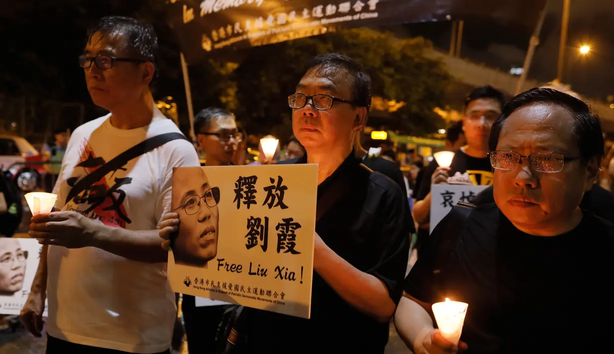 Massa menyalakan lilin dan membawa poster penerima Nobel Perdamaian, Liu Xiaobo, untuk mengenang kematian tokoh pro demokrasi itu di Hong Kong, Sabtu (15/7). Jasad Liu Xiaobo dikremasi, dan abunya dilarung ke laut, Sabtu ini. (AP Photo/Vincent Yu)