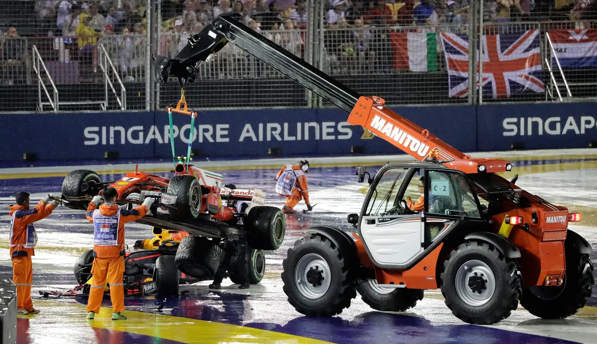 Sebuah mobil penyelamat mengangkat mobil pembalap Ferrari, Kimi Raikkonen dan mobil Red Bull Max, Verstappen setelah bertabrakan pada awal Grand Prix Singapura Formula One di Sirkuit Marina Bay City, Singapura, Minggu, (17/09). (AP Photo / Wong Maye-E)