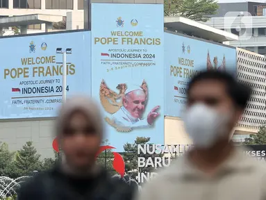 Warga berjalan di depan layar Light Emitting Diode (LED) yang bertuliskan ucapan selamat datang Pope Francis di kawasan Bundaran Hotel Indonesia, Jakarta, Minggu (1/9/2024). (Liputan6.com/Angga Yuniar)