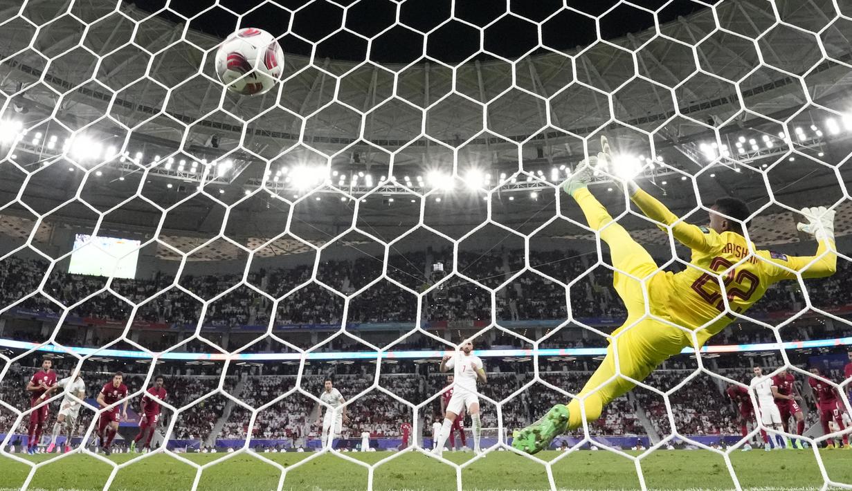 Kiper Iran, Meshaal Barsham gagal menghalau bola tendangan penalti pemain Iran, Alireza Jahan Bakhsh pada laga semifinal Piala Asia 2023 di Al Thumama Stadium, Doha, Qatar, Rabu (07/02/2024). (AFP/Aijaz Rahi)